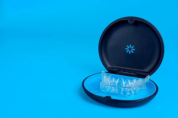 Set of clear aligners resting in an Invisalign® branded case on a blue background at Douglas A. Block, DDS & Charles G. Kocun, DMD in Manalapan, NJ